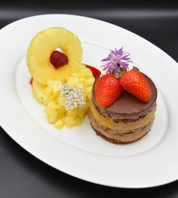 Schokolademousse Törtchen und Ananas Salat serviert auf Himbeercoulis